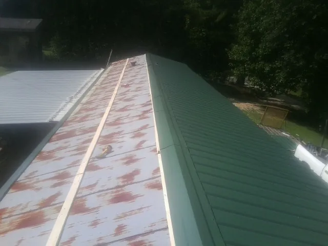 Old rusted panels beside newly installed green metal roofing — Wind Damage Roof Repair by Roofing Brothers in Morgantown